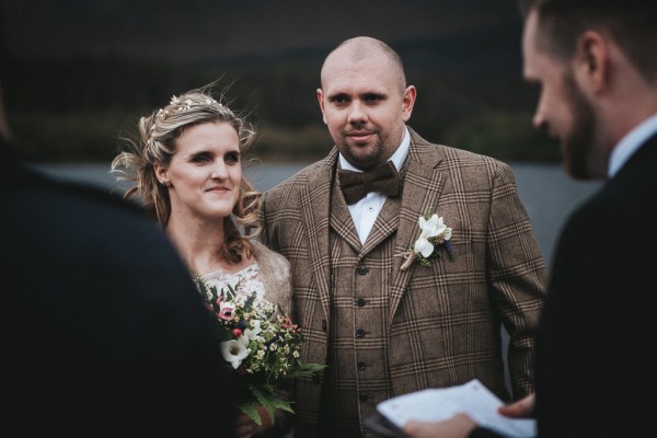 Bride and groom smile with celebrant reading sermon