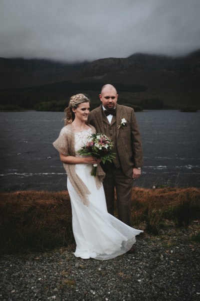 Bride and groom stand smiling in front of celebrant