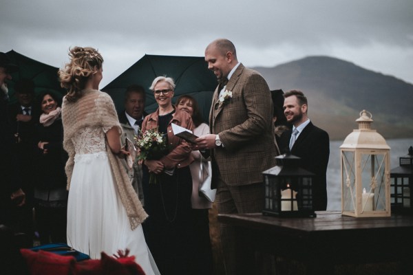 Groom bride and celebrant reading vows and guests