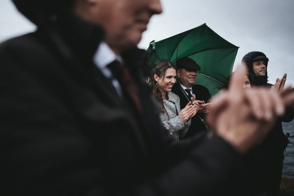 Guests clapping under umbrellas