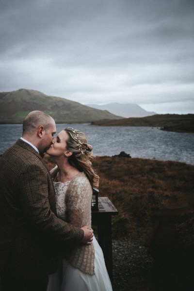 Bride and groom kiss sea and mountains in background