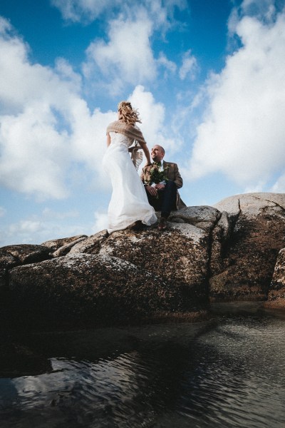 Bride and groom on top of mountainous rocks skyline and clouds