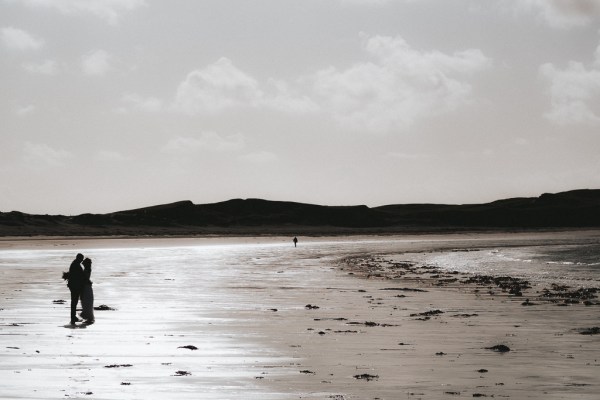 Bride and groom walking on the beach in the distance