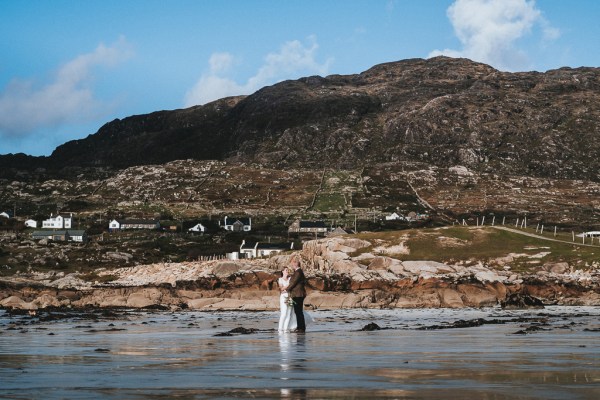 Couple on pier sea lake rocks beach setting mountains in background walking along main road