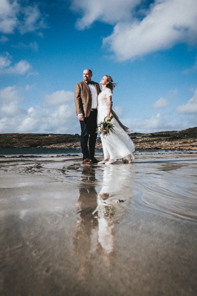 Bride and groom embrace on the beachy sand beach rocks mountains