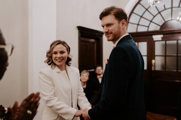 Bride and groom smile during ceremony holding hands