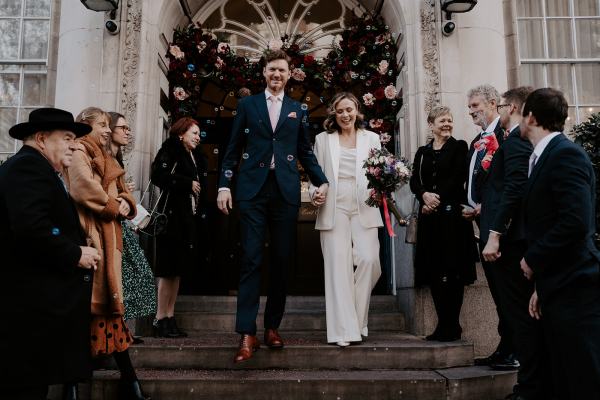 Bride and groom walk down the steps after ceremony ended guests clap and throw confetti on couple