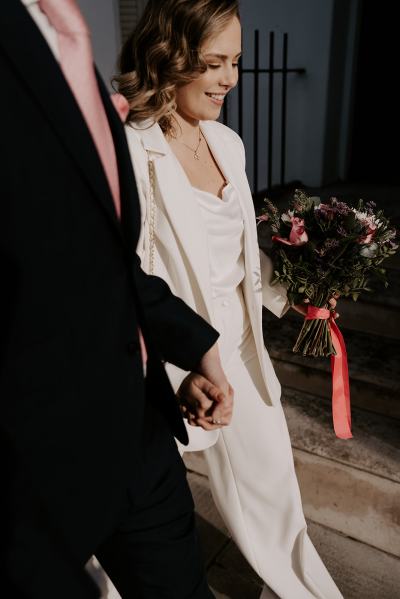 Bride and groom walk hand in hand together in the sun