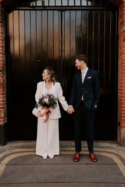 Bride looks away groom looks at her outside large black door entrance