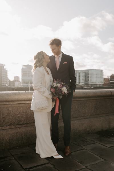 Bride and groom face each other in the winter sun landscape buildings in background