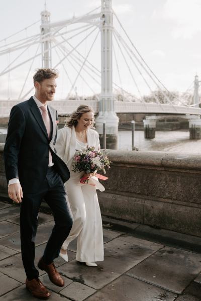 Landscape in background bride and groom walk holding hands both looking down