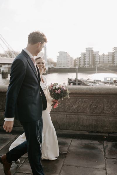 Landscape in background bride and groom walk holding hands smiling at each other