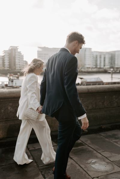 Side view of bride and groom walking pathway landscape in background holding hands