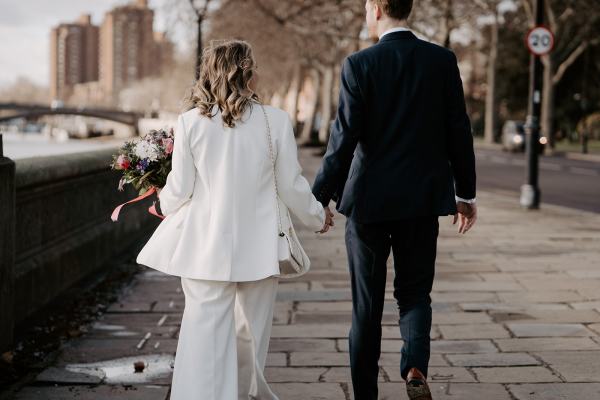 Bride and groom walking from behind holding hands bouquet