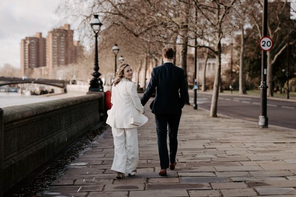 Bride and groom walking from behind holding hands bouquet she looks over her shoulder