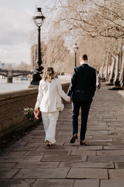 Bride and groom walking from behind holding hands bouquet