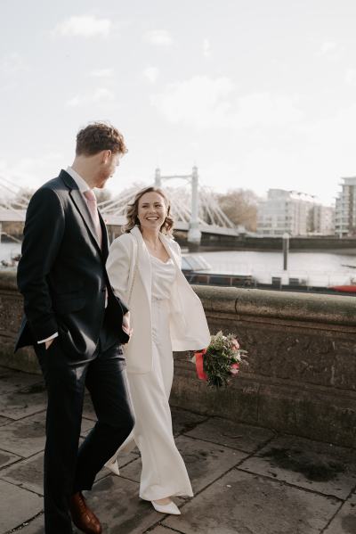 Landscape in background bride and groom walk holding hands smiling at each other