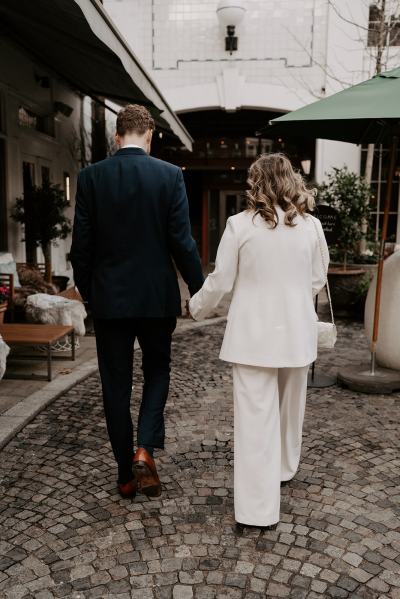 Bride and groom from behind walking hand in hand away from camera