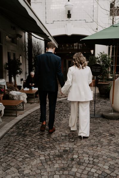 Bride and groom from behind walking hand in hand away from camera