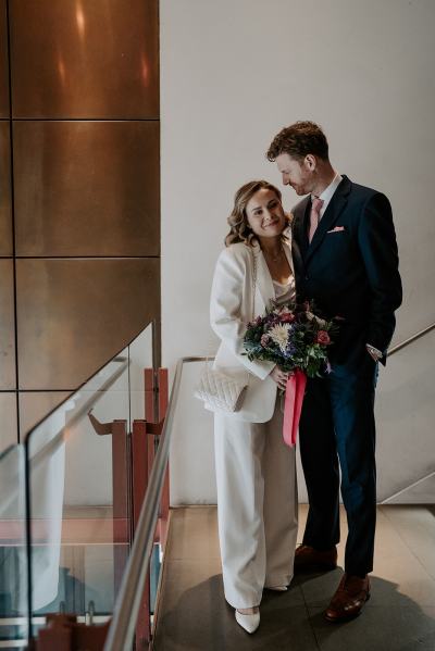 Bride and groom at top of stairs he looks at her