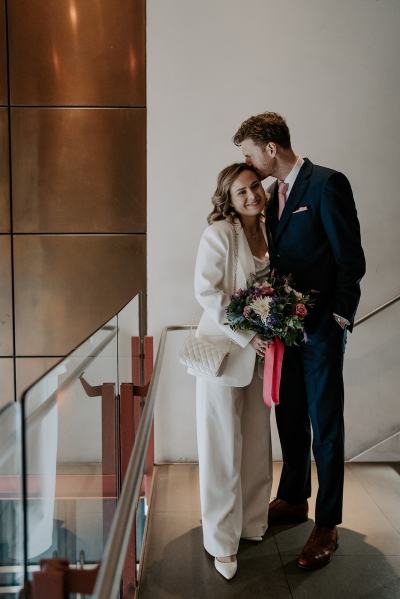 Bride and groom at top of stairs he kisses her on the head