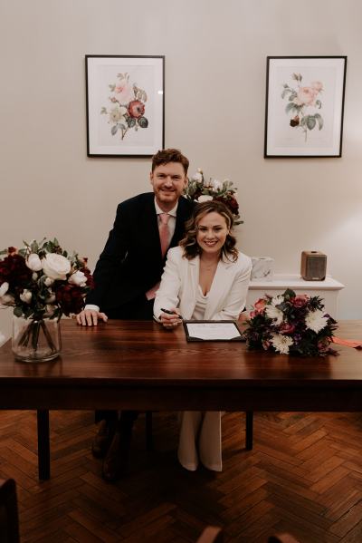 Bride and groom signing the marriage certificate smiling