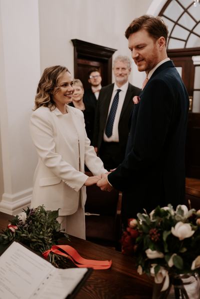 Bride and groom smile during ceremony holding hands