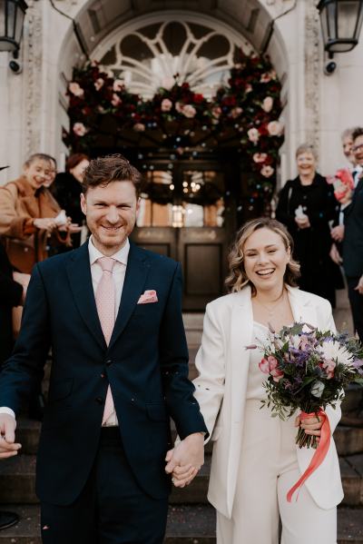 Bride and groom walk down the steps after ceremony ended guests clap and throw confetti on couple