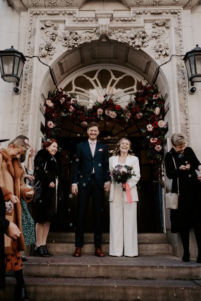 Bride and groom walk down the steps after ceremony ended guests clap and throw confetti on couple