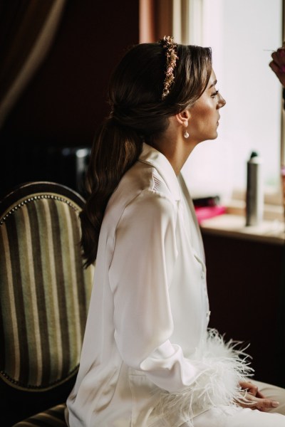 Bride wears feather bridal loungewear as she sits waiting to get ready