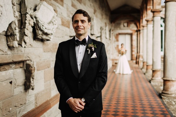 Bride walks up to groom to approach him, she waits behind him on the tiles