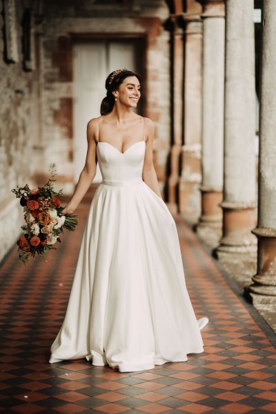 Bride stands on tiles holding bouquet pillars in background