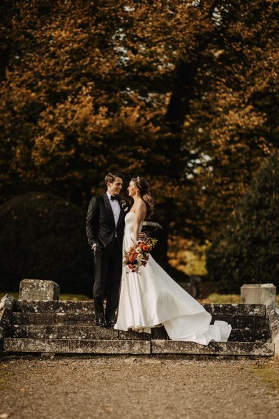 Bride holds bouquet to one side as she looks at her groom husband