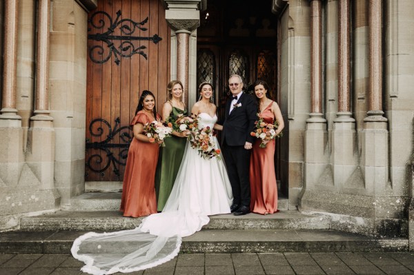 Bride father bridesmaids stand at cathedral entrance