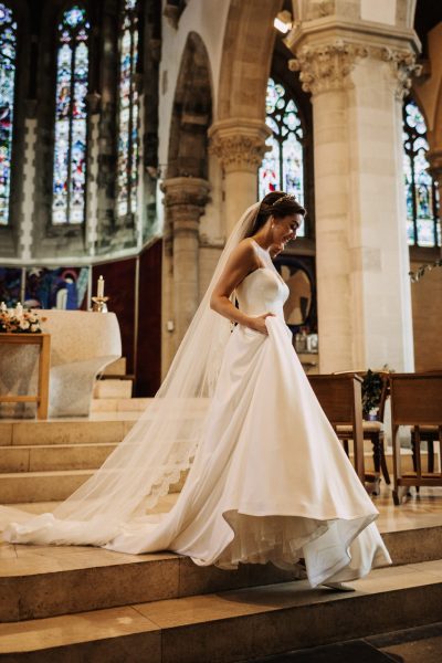 Bride makes her way down the steps holding up her dress