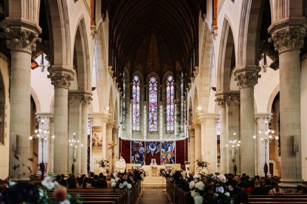 View of cathedral alter, tinted window frames and guests seated in pews