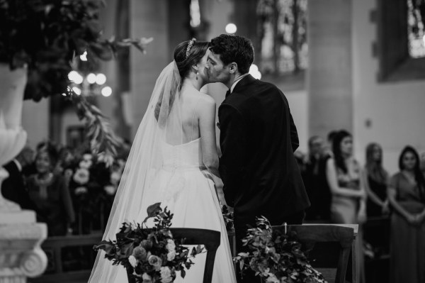 Bride and groom kiss kissing at alter black and white