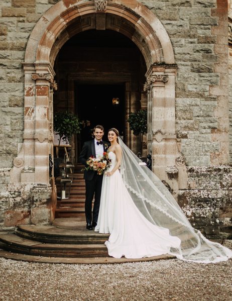 Bride and groom stand on steps exterior to cathedral church