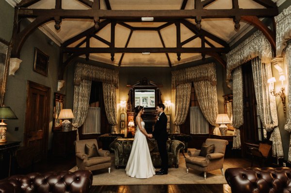 Bride and groom stand in marquee room holding hands facing each other tent