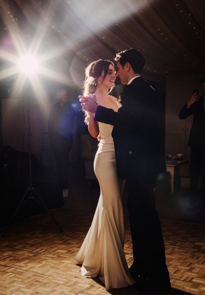 Bride and groom dance on the dancefloor guests watch spotlight