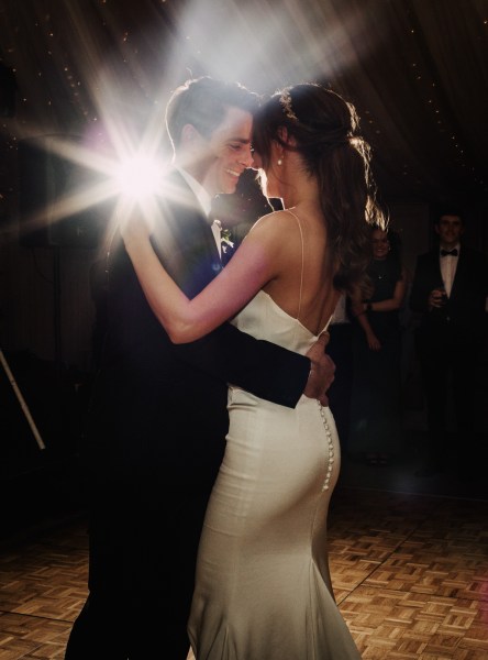 Couple bride and groom dance on the dancefloor spotlight behind them