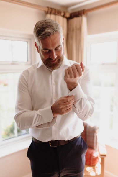 Groom gets ready and fixes his white shirt