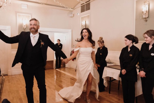 Bride and groom enter ballroom guests are cheering