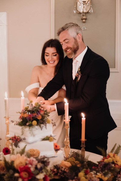 Bride and groom cutting the white wedding cake