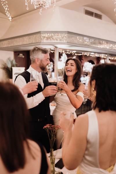 Bride groom and guests at dining room table they laugh