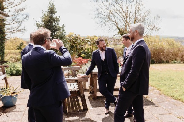 Groom and groomsmen have beverages in the garden