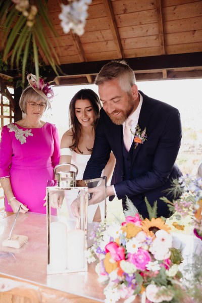 Bride groom and mother witness, they light a candle together