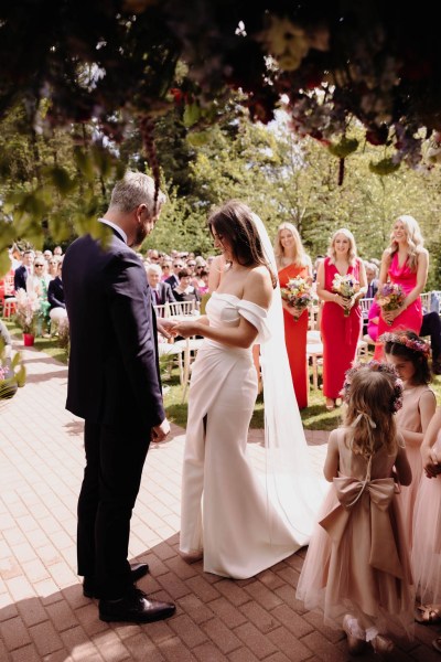 Bride groom little girls and bridesmaids in background during ceremony