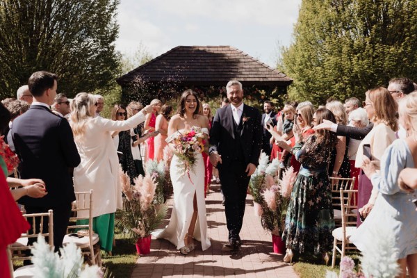 Bride and groom just wed leaving ceremony guests clap and celebrate