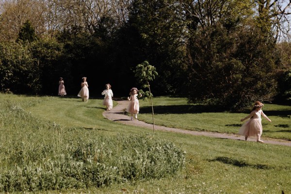 Little girls run in a row down the pathway to garden